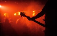 Silhouetted guitarist performing under intense red-orange concert lights